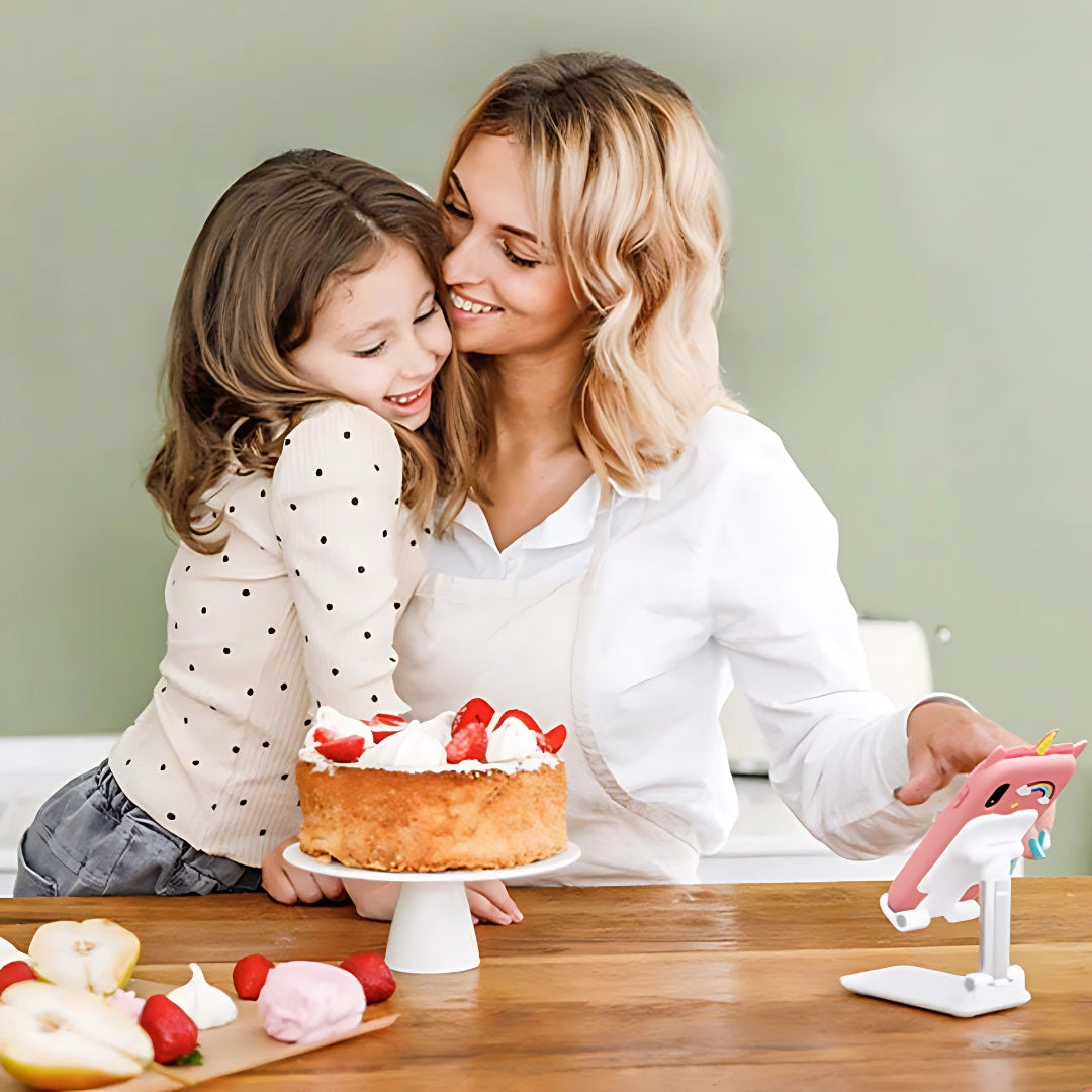 Entillio™ kids learning phone in pink, held by a woman, with a girl smiling beside a cake on a wooden table.