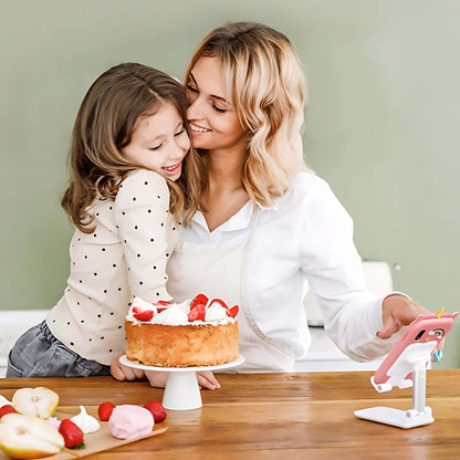 Entillio™ kids learning phone in pink, held by a woman, with a girl smiling beside a cake on a wooden table.